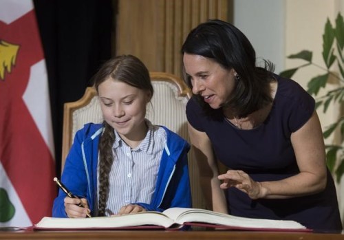 Swedish climate activist Greta Thunberg, left, signs the Golden Book next to Montreal Mayor Valerie Plante during a ceremony in Montreal, Friday, Sept. 27, 2019. The 