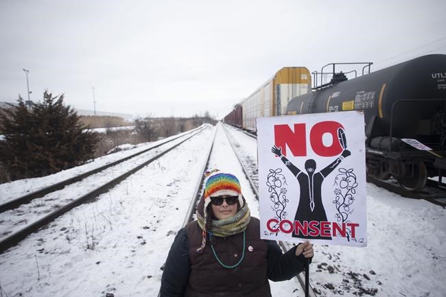 A protester holds a placard as supporters of the Wet'suwet'en hereditary chiefs demonstrate at Macmillan Yard in Toronto, Saturday, Feb. 15, 2020. In the last month, Indigenous people across the country set up barricades on train tracks, roads and bridges, in solidarity with Wet'suwet'en Nation hereditary chiefs, some of whom object to the construction of a natural-gas pipeline through their traditional territory. THE CANADIAN PRESS/Chris Young