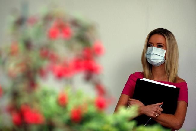 White House press secretary Kayleigh McEnany listens as President Donald Trump speaks about the coronavirus during a press briefing in the Rose Garden of the White House, Monday, May 11, 2020, in Washington. (AP Photo/Alex Brandon)