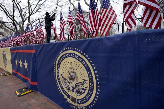 A worker installs flags on Pennsylvania Avenue in front of the White House ahead of President-elect Joe Biden's inauguration ceremony, Tuesday, Jan. 19, 2021, in Washington. (AP Photo/David Phillip)
