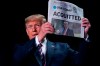 President Donald Trump holds up a newspaper with the headline that reads 