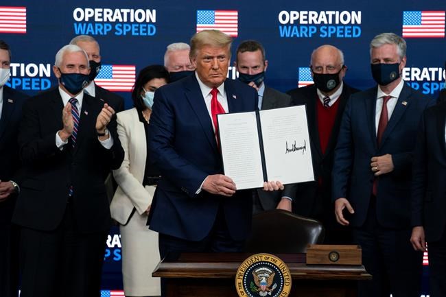 President Donald Trump shows an executive order on vaccine distribution during an