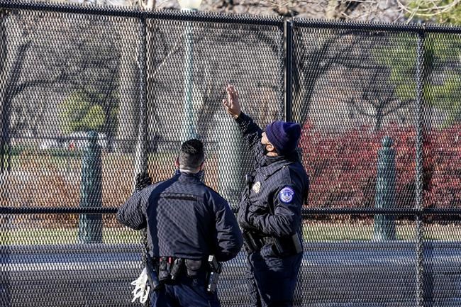 Capitol police officers look at fencing that was installed around the exterior of the Capitol grounds, Thursday, Jan. 7, 2021 in Washington. The House and Senate certified the Democrat's electoral college win early Thursday after a violent throng of pro-Trump rioters spent hours Wednesday running rampant through the Capitol. A woman was fatally shot, windows were bashed and the mob forced shaken lawmakers and aides to flee the building, shielded by Capitol Police. (AP Photo/John Minchillo)