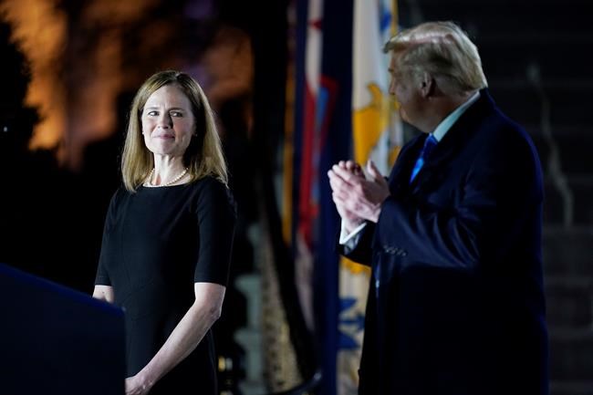President Donald Trump looks toward Amy Coney Barrett, before Supreme Court Justice Clarence Thomas administers the Constitutional Oath to her on the South Lawn of the White House in Washington, Monday, Oct. 26, 2020, after Barrett was confirmed by the Senate earlier in the evening. (AP Photo/Patrick Semansky)