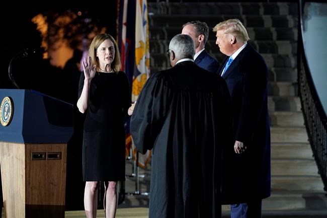 President Donald Trump watches as Supreme Court Justice Clarence Thomas administers the Constitutional Oath to Amy Coney Barrett on the South Lawn of the White House in Washington, Monday, Oct. 26, 2020, after Barrett was confirmed by the Senate earlier in the evening. (AP Photo/Patrick Semansky)