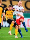 Hamburg's Toni Leistner, right, and Dresden's Christoph Daferner, left, challenge for the ball during the German soccer cup (DFB Pokal) first round match between SG Dynamo Dresden and Hamburger SV in Dresden, Germany, Monday, Sept. 14, 2020. Hamburg defender Toni Leistner has been banned for three games for assaulting a fan who he said had insulted his family. Leistner leapt into the stand during a TV interview and pushed a Dynamo Dresden fan after Dresden had beaten Hamburg 4-1 in their German Cup game Monday. (Robert Michael/dpa via AP)