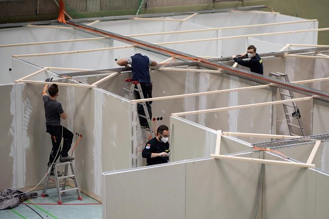 Workers of the Federal Agency for Technical Relief (THW) are setting up a vaccination centre in the sports hall of a school in Eschwege, Germany, Tuesday, Dec. 1, 2020. The German government is preparing to roll out a nationwide coronavirus vaccination program. (Sven Pfoertner/dpa via AP)