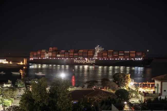 A cargo ship sails through the town of Suez, Egypt, Tuesday, March 30, 2021 as traffic resumed through the Suez canal after it was blocked by a massive ship that had been stuck sideways for nearly a week. (AP Photo/Mohamed Elshahed)