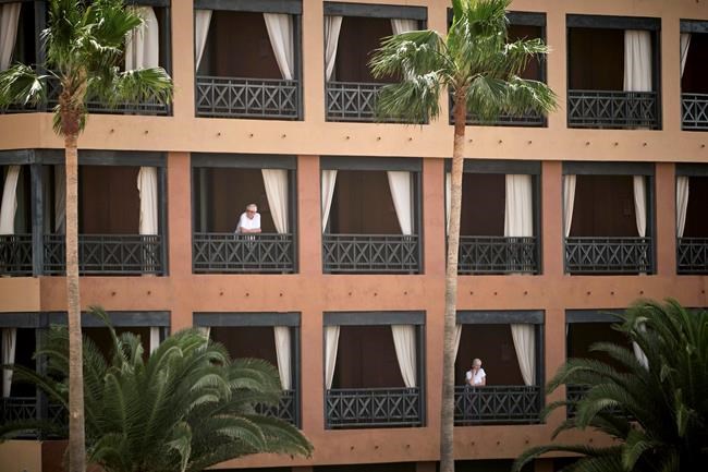People stand at their balconies at the H10 Costa Adeje Palace hotel in Tenerife, Canary Island, Spain, Tuesday, Feb. 25, 2020. Spanish officials say a tourist hotel on the Canary Islands has been placed in quarantine after an Italian doctor staying there tested positive for the new coronavirus. (AP Photo)