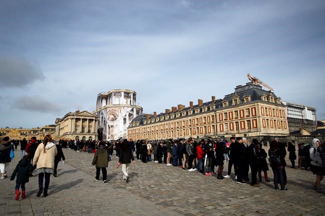 Visitors stand in line to enter the Chateau de Versailles, west of Paris, Tuesday, March 3, 2020. The Chateau de Versailles remains open after management met with staff worried about the spread of the new virus. (AP Photo/Christophe Ena)