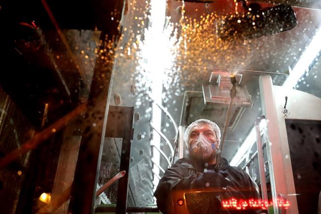 A worker disinfects a public bus against coronavirus in Tehran, Iran, in early morning of Wednesday, Feb. 26, 2020. Iran's government said Tuesday that more than a dozen people had died nationwide from the new coronavirus, rejecting claims of a much higher death toll of 50 by a lawmaker from the city of Qom that has been at the epicenter of the virus in the country. (AP Photo/Ebrahim Noroozi)