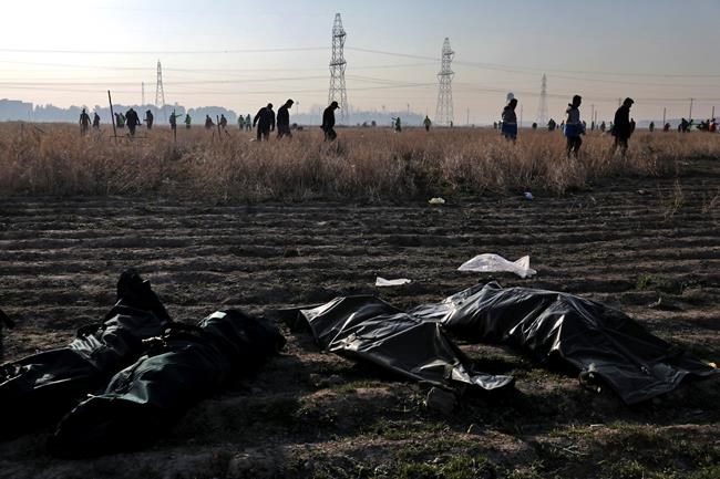 Rescue workers search the scene where a Ukrainian plane crashed as the bodies of victims in body bags lie on the ground, in Shahedshahr, southwest of the capital Tehran, Iran, Wednesday, Jan. 8, 2020. A Ukrainian airplane with more than 170 people crashed on Wednesday shortly after takeoff from Tehran's main airport, killing all onboard. (AP Photo/Ebrahim Noroozi)