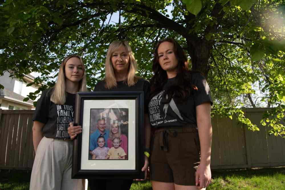 ALEX LUPUL / WINNIPEG FREE PRESS  
Jo-Anne McNeil holds a family photo with her daughters Sarah and Taylor. Jo-Anne's husband Pat McNeil is weeks away from dying of brain cancer but he can only see his wife while in palliative care, not their daughters.