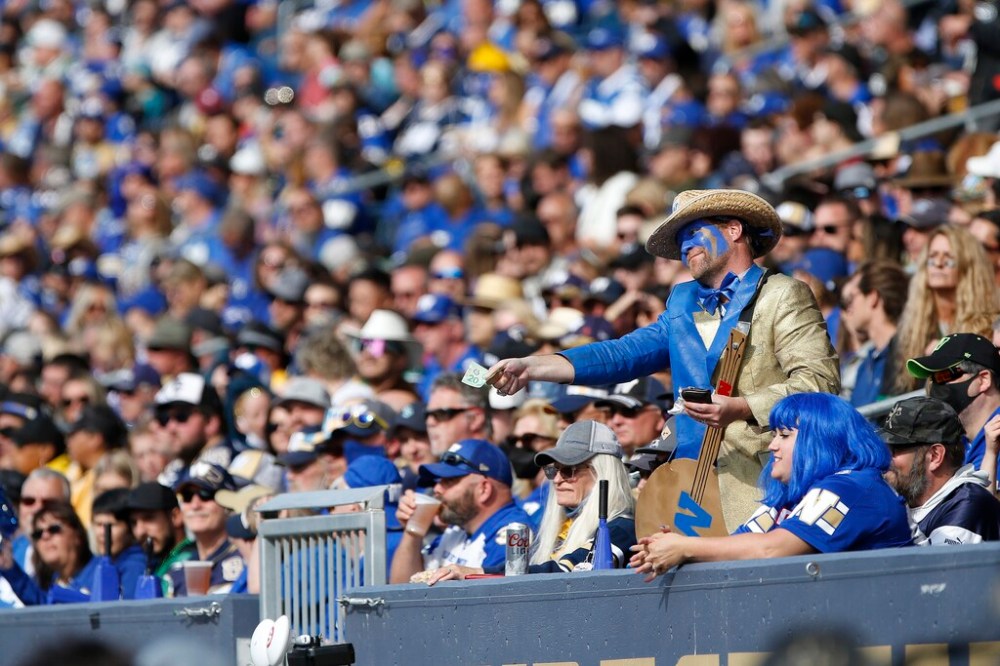 CP
A Winnipeg Blue Bomber fan offers the Saskatchewan Roughriders' bench $20 during Saturday's Banjo Bowl. (John Woods / The Canadian Press files)