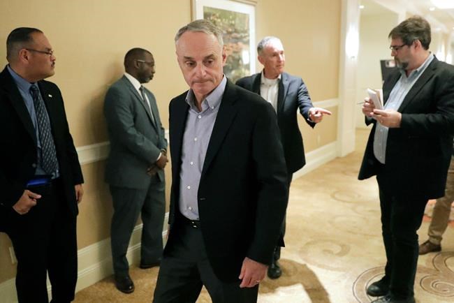 MLB Commissioner Rob Manfred, center, leaves a press conference during MLB baseball owners meetings, Thursday, Feb. 6, 2020, in Orlando, Fla. (AP Photo/John Raoux)