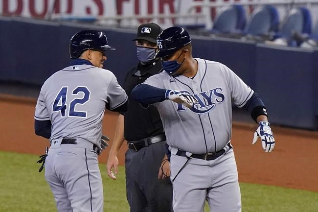 Tampa Bay Rays' Willy Adames, left, is congratulated by first base coach Ozzie Timmons after getting a base hit during the first inning of a baseball game against the Miami Marlins, Sunday, Aug. 30, 2020, in Miami. (AP Photo/Wilfredo Lee)