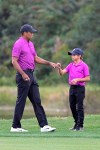 Tiger Woods, left, shares a fist-bump with his son Charlie after walking up their ball on the 14th fairway during the first round of the PNC Championship golf tournament, Saturday, Dec. 19, 2020, in Orlando, Fla. (AP Photo/Phelan M. Ebenhack)