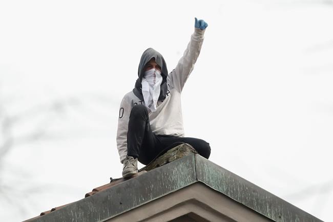 A man stands on the roof of the San Vittore prison as some inmates stage a protest against new rules to cope with coronavirus emergency, in Milan, Italy, Monday, March 9, 2020. Italy took a page from China's playbook Sunday, attempting to lock down 16 million people — more than a quarter of its population — for nearly a month to halt the relentless march of the new coronavirus across Europe. (AP Photo/Antonio Calanni)