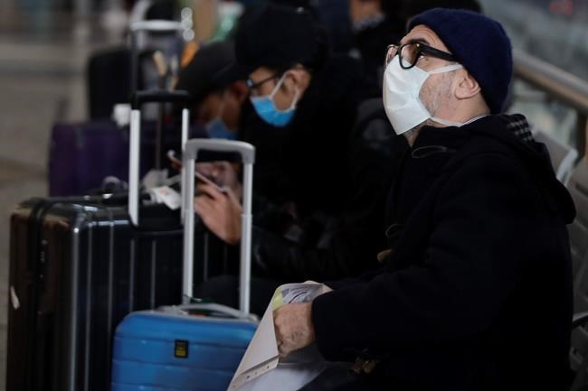 People wearing sanitary masks sit as they wait at the Centrale main railway station in Milan, Italy, Monday, Feb. 24, 2020. Italy has been scrambling to check the spread of Europe's first major outbreak of the new viral disease amid rapidly rising numbers of infections and a third death, calling off the popular Venice Carnival, scrapping major league soccer matches in the stricken area and shuttering theaters, including Milan's legendary La Scala. (AP Photo/Luca Bruno)
