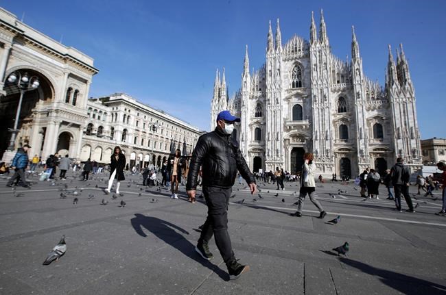 A man wearing a sanitary mask walks past the Duomo gothic cathedral in Milan, Italy, Monday, Feb. 24, 2020. Italy has been scrambling to check the spread of Europe's first major outbreak of the new viral disease amid rapidly rising numbers of infections and calling off the popular Venice Carnival, scrapping major league soccer matches in the stricken area and shuttering theaters, including Milan's legendary La Scala. (AP Photo/Luca Bruno)