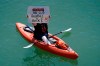 A woman kayaker holds up a sign in McCovey Cove before the start of an opening day baseball game between the San Francisco Giants and the Colorado Rockies, Friday, April 9, 2021, in San Francisco. (AP Photo/Eric Risberg)