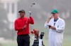 Tiger Woods prepares to hits his second shot on the first fairway with caddie Joe LaCava looking on during the final round of the Masters golf tournament Sunday, Nov. 15, 2020, in Augusta, Ga. (Curtis Compton/Atlanta Journal-Constitution via AP)