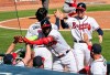 Atlanta Braves' Marcell Ozuna, center, is greeted at the dugout after hitting a two-run home run in the eighth inning against the Cincinnati Reds in Game 2 of a National League wild-card baseball series, Thursday, Oct. 1, 2020, in Atlanta. (Curtis Compton/Atlanta Journal-Constitution via AP)
