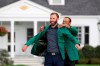 Last year's Masters champion Tiger Woods, right, presents Dustin Johnson his first green jacket after winning the Masters golf tournament Sunday, Nov. 15, 2020, in Augusta, Ga. (Curtis Compton/Atlanta Journal-Constitution via AP)