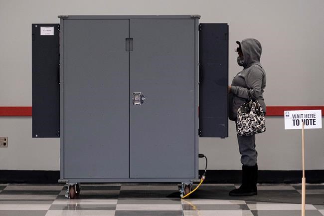A voter casts her ballot at the C.T. Martin Natatorium and Recreation Center in Atlanta on the first day of early voting for the senate runoff Monday, Dec. 14, 2020. Early in-person voting began Monday in Georgia for the state's twin U.S. Senate runoffs. The early voting period runs as late as Dec. 31 in some counties. It could determine the outcome of the races between Republican U.S. Sens. David Perdue and Kelly Loeffler and Democratic challengers Jon Ossoff and Raphael Warnock. (AP Photo/Ben Gray)