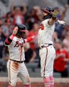 Atlanta Braves' Dansby Swanson, right, celebrates with Ozzie Albies after hitting a home run off Philadelphia Phillies' Aaron Nola during the first inning of a baseball game Sunday, May 9, 2021, in Atlanta. (AP Photo/Ben Margot)