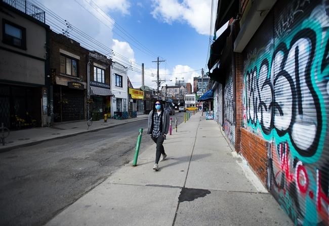 A lone person walks past closed businesses in Kensington Market in Toronto on Wednesday, April 15, 2020. As the federal government begins accepting applications for the Canada Emergency Wage Subsidy to soften the economic blow of the COVID-19 outbreak, many business owners wonder if their own wages are covered. THE CANADIAN PRESS/Nathan Denette