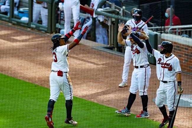 Atlanta Braves' Ronald Acuna Jr., left, celebrates from a distance as he approaches the dugout after hitting a two-run home run to center field during the fourth inning of the first game in a doubleheader baseball game against the Washington Nationals, Friday, Sept. 4, 2020, in Atlanta. (AP Photo/John Amis)