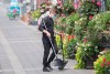 A man wears a face mask and shield as he cleans the sidewalk next to an outdoor terrace in Montreal, Sunday, July 5, 2020, as the COVID-19 pandemic continues in Canada and around the world. THE CANADIAN PRESS/Graham Hughes