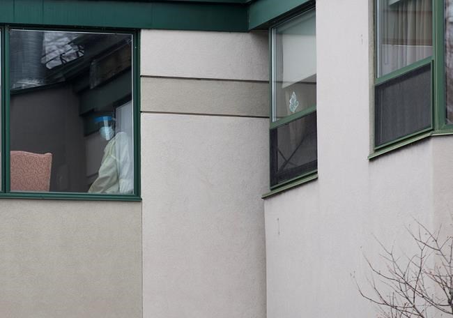 A healthcare worker looks out of a window at Maison Herron, a long term care home in the Montreal suburb of Dorval, Que., on Saturday, April 11, 2020, as COVID-19 cases rise in Canada and around the world. THE CANADIAN PRESS/Graham Hughes