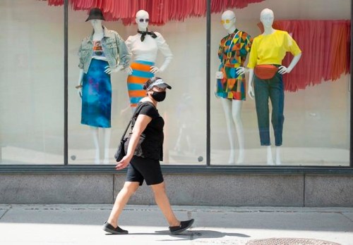 A woman wears a face mask as she walks along Sainte-Catherine street in Montreal, Sunday May 24, 2020, as the COVID-19 pandemic continues in Canada and around the world. Stores with a street entrance are allowed to reopen in Montreal on May 25th. THE CANADIAN PRESS/Graham Hughes