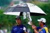 Webb Simpson keeps dry as his caddie dries off his club on the 13th green during the final round of the Sony Open PGA Tour golf event, Sunday, Jan. 12, 2020, at Waialae Country Club in Honolulu. (AP Photo/Matt York)