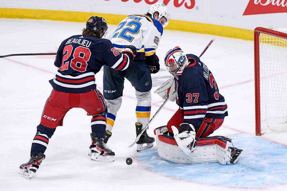 CP
Winnipeg Jets goaltender Connor Hellebuyck (37) makes a save on St. Louis Blues' Logan Brown (22) as he is defended by Nathan Beaulieu (28) during third period. (Fred Greenslade / The Canadian Press)