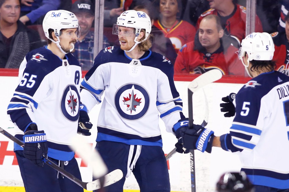 CP
Kyle Connor (centre) celebrates his game-winning goal against Calgary Mark Scheifele (left) and Brenden Dillon. It was his second of the night. (Larry Mac Dougal / The Canadian Press)