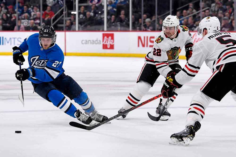 Winnipeg Jets' Nikolaj Ehlers (27) carries the puck past Chicago Blackhawks' Ryan Carpenter (22) and Connor Murphy (5) during the second period. (Fred Greenslade / The Canadian Press)