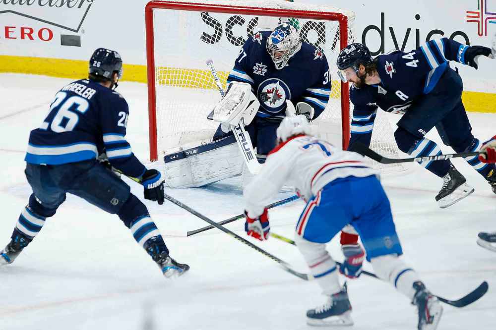 Winnipeg Jets goaltender Connor Hellebuyck (37) makes the save on Montreal Canadiens' Tyler Toffoli (73) as Blake Wheeler (26) and Josh Morrissey (44) defend during the first period. (John Woods / The Canadian Press)