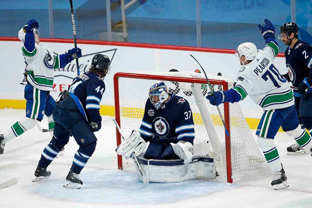Vancouver Canucks' Nils Hoglander (36) and Tanner Pearson (70) celebrate Hoglander’s goal against Winnipeg Jets goaltender Connor Hellebuyck (37) as Jets' Josh Morrissey (44) and Dylan DeMelo (2) defend during first period NHL action in Winnipeg on Saturday, January 30, 2021. (John Woods / The Canadian Press)
