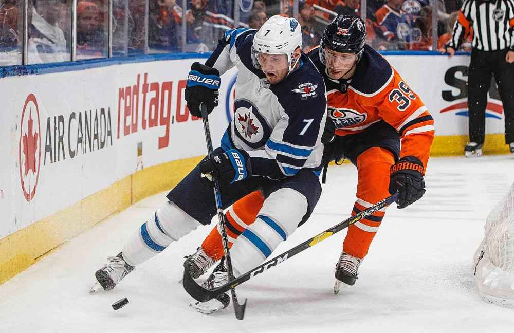 Winnipeg Jets' Dmitry Kulikov (7) is chased by Edmonton Oilers' Alex Chiasson (39) during the second period. (Jason Franson / The Canadian Press)