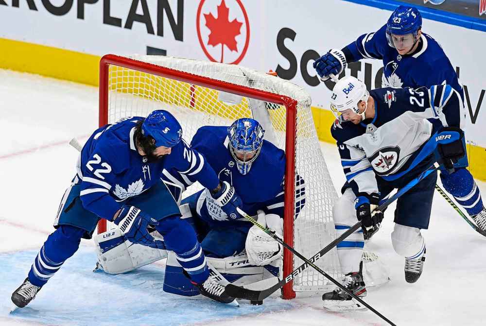 Toronto Maple Leafs goaltender Frederik Andersen (31) makes a save on Winnipeg Jets centre Trevor Lewis (23) as Maple Leafs' Zach Bogosian (22) and Travis Dermott (23) defend during first period NHL action in Toronto on Saturday, March 13, 2021. THE CANADIAN PRESS/Frank Gunn