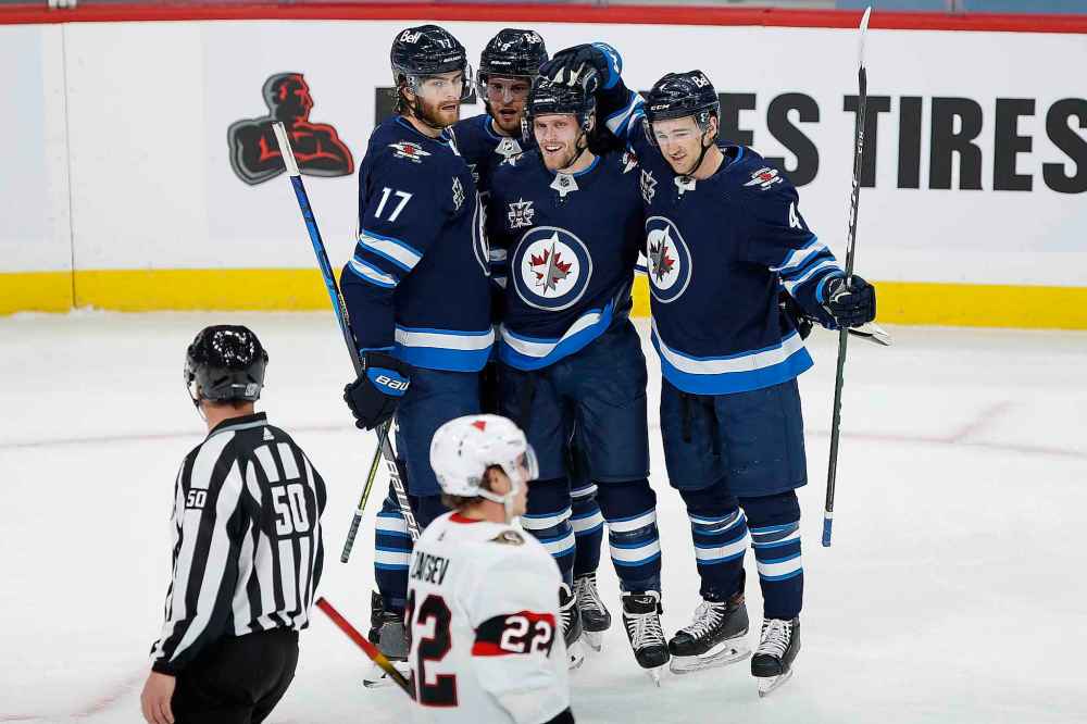 Winnipeg Jets' Adam Lowry (17) , Andrew Copp (9), Nikolaj Ehlers (27) and Neal Pionk (4) celebrates Ehlers’ goal against the Ottawa Senators during first period NHL action in Winnipeg on Saturday, January 23, 2021. (John Woods / The Canadian Press)