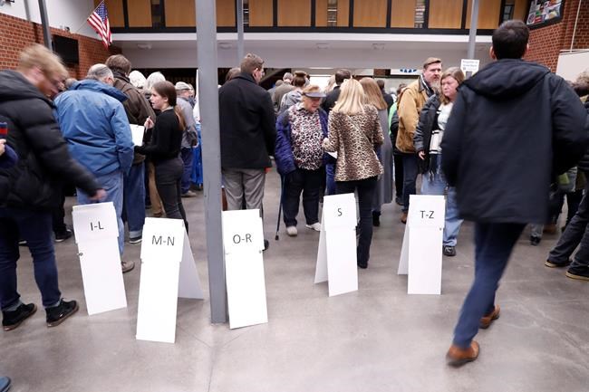 Signs guide caucus goers as they arrive at a caucus at Roosevelt Hight School, Monday, Feb. 3, 2020, in Des Moines, Iowa. (AP Photo/Andrew Harnik)