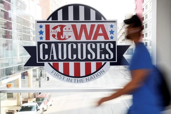 A pedestrian walks past a sign for the Iowa Caucuses on a downtown skywalk, Tuesday, Feb. 4, 2020, in Des Moines, Iowa. (AP Photo/Charlie Neibergall)