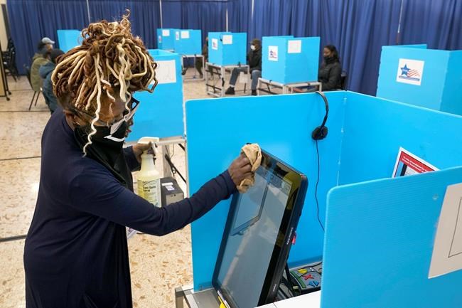 Poll captain Monique White sanitizes an electronic voting machine on Election Day, Tuesday, Nov. 3, 2020, at the Dr. Martin Luther King Community Center in the Bronzeville neighborhood of Chicago. (AP Photo/Charles Rex Arbogast)