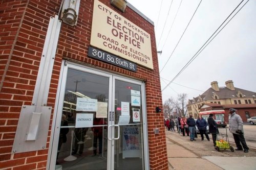 People stand in line to vote at the City of Rockford Election Office on Monday, March 16, 2020, in Rockford, Ill. Gov. J.B. Pritzker and state officials said Monday that despite restaurants, bars and other businesses being ordered closed, the Illinois Primary will be held as planned. (Scott P. Yates/Rockford Register Star via AP)
