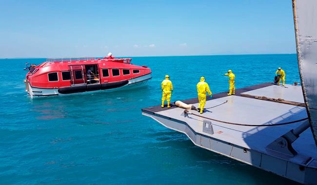 In this photo released Indonesian Military, military personnel in protective suits direct a life boat carrying Indonesian crew members from the World Dream cruise ship as they are transferred to hospital ship KRI Dr. Soeharso on the waters of Durian Bay, Indonesia, Wednesday, Feb. 26, 2020. Indonesia evacuates 188 of its citizens from the cruise ship Wednesday after they were released from quarantine in Hong Kong following tests that found no infections of COVID-19. (Indonesian Military via AP)