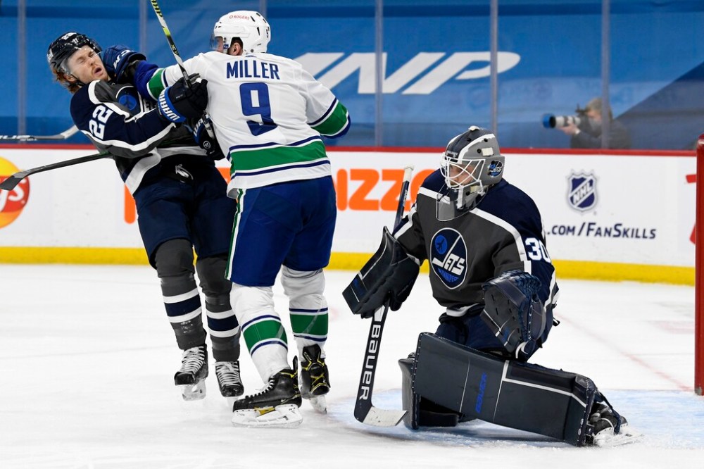 Winnipeg Jets' Mason Appleton is hit by Vancouver Canucks' J.T. Miller in front of goaltender Laurent Brossoit during the first period. THE CANADIAN PRESS/Fred Greenslade
